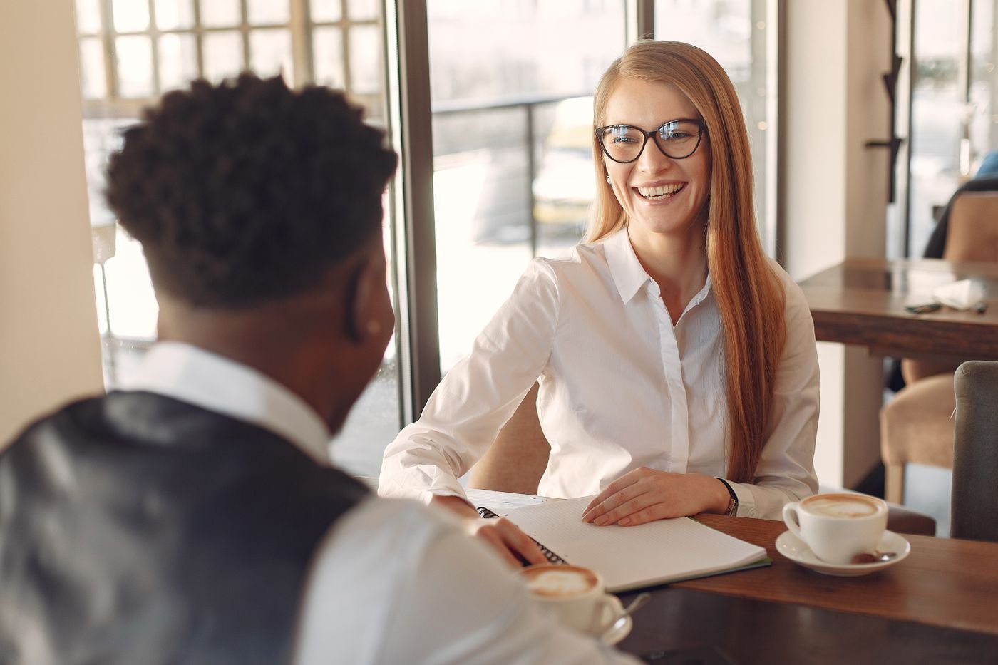 Two professionals in a warm one-to-one conversation over coffee